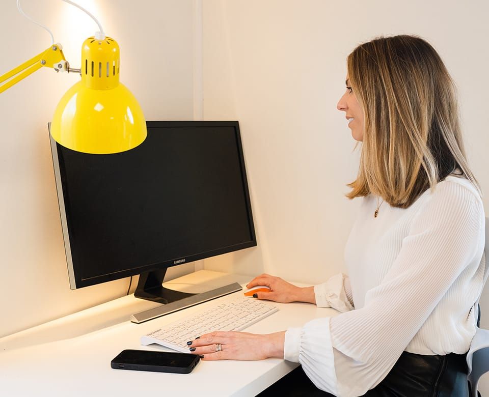 A Get Ahead virtual specialist working at a desktop computer beside a yellow desk lamp.