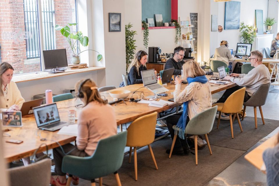 People working at a shared table inside the Well & Good coworking space in Godalming.