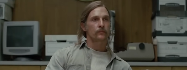 Detective Rust Cohle from True Detective in a crowded police station room.