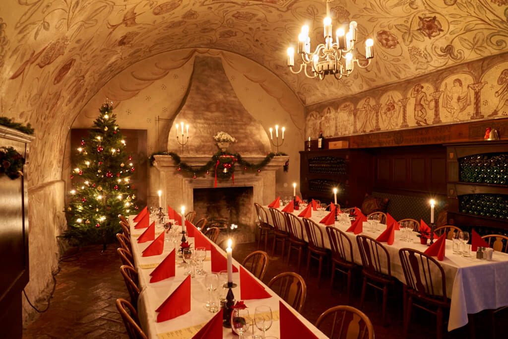 Mysigt uppdukade bord med juldekorationer och en julgran i bakgrunden