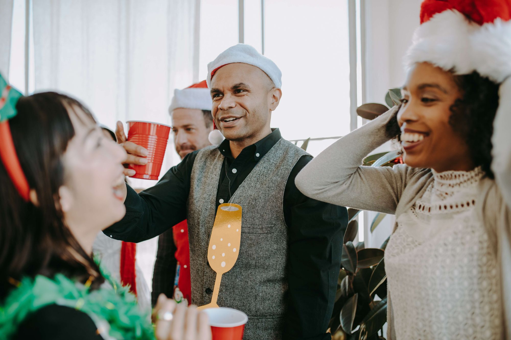 Glada kollegor med tomteluvor på julfest på jobbet
