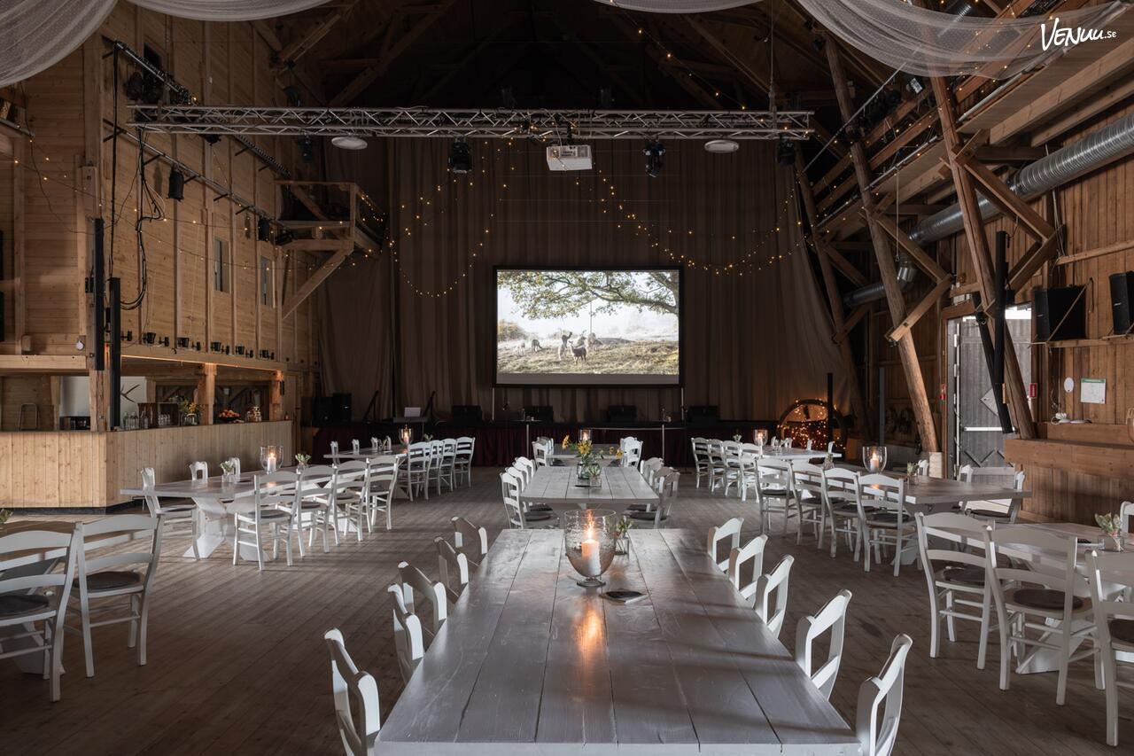 Logen på Siggesta Gård – en rymlig lada med loft, scen och rustik inredning för personliga bröllop.