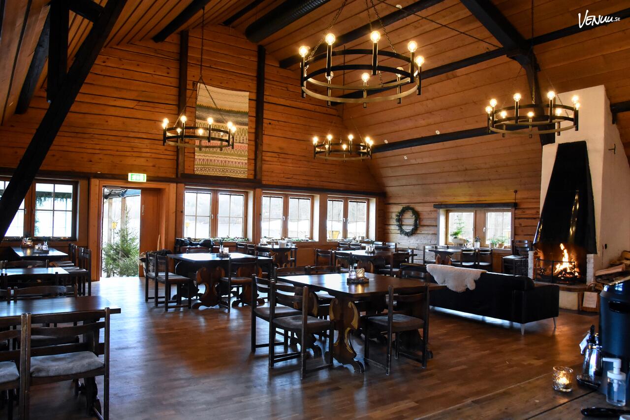 En mysig restauranglokal i en naturnära miljö, med trädetaljer och utsikt mot grönskan.