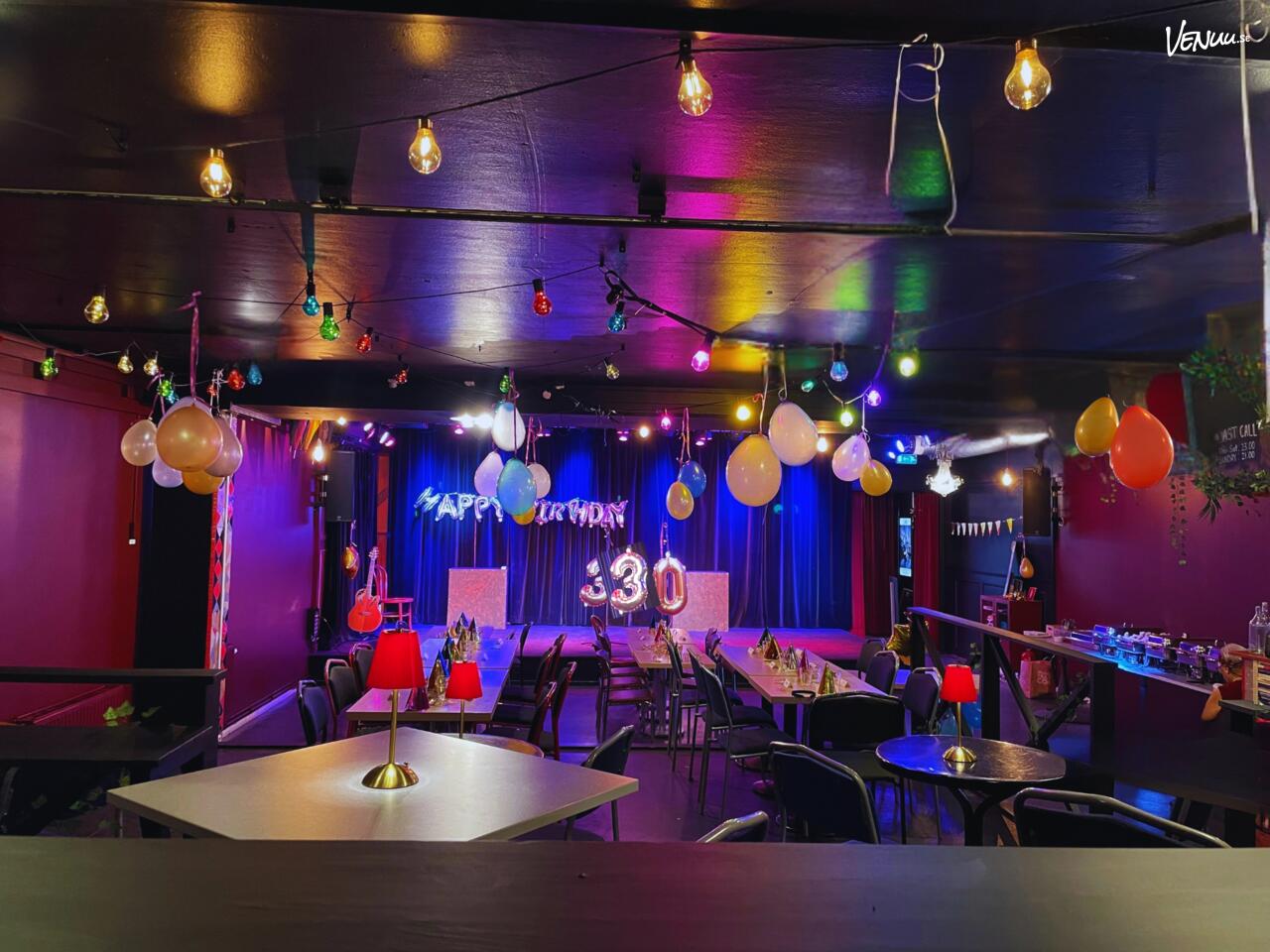 En stämningsfull bild från en teater eller bar med en scen och sittplatser, redo för underhållning och samtal.