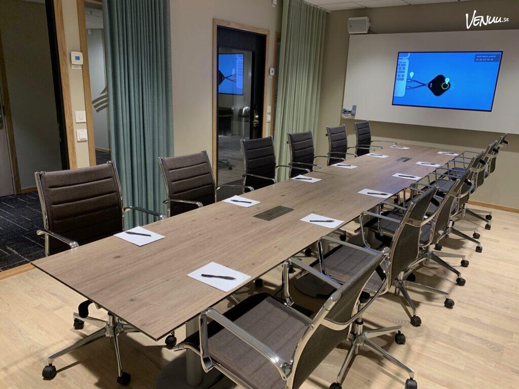 Ett funktionellt och modernt konferensrum med bekväma stolar och en stor skärm, lämpligt för möten.