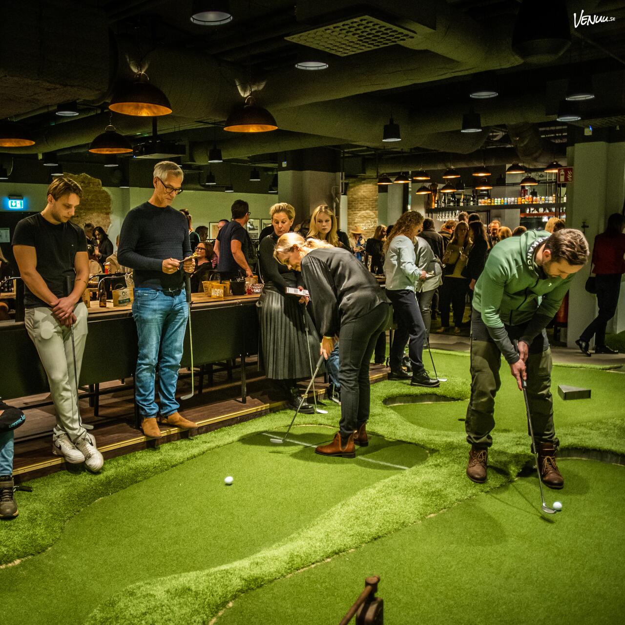 En lekfull och aktiv lokal med minigolfbanor och en bar där människor umgås och spelar.