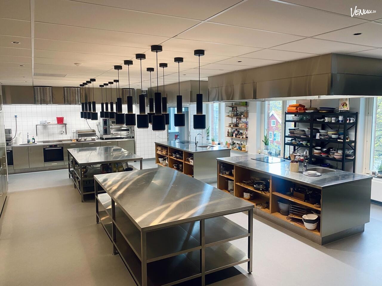 En industriell och rå matstudio med tegelväggar och moderna köksutrustningar, där deltagare fokuserar på matlagning.