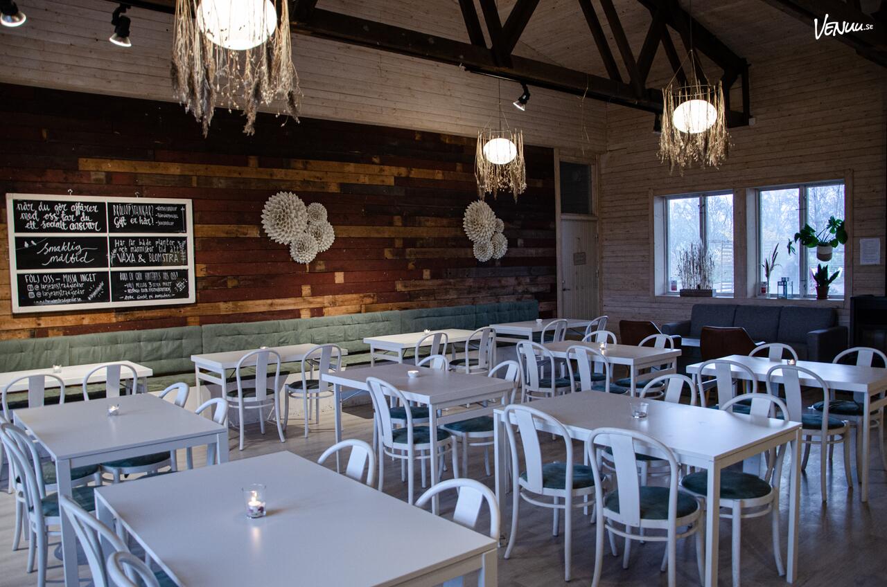 En charmig klubbstuga omgiven av en grönskande trädgård med sittplatser utomhus.