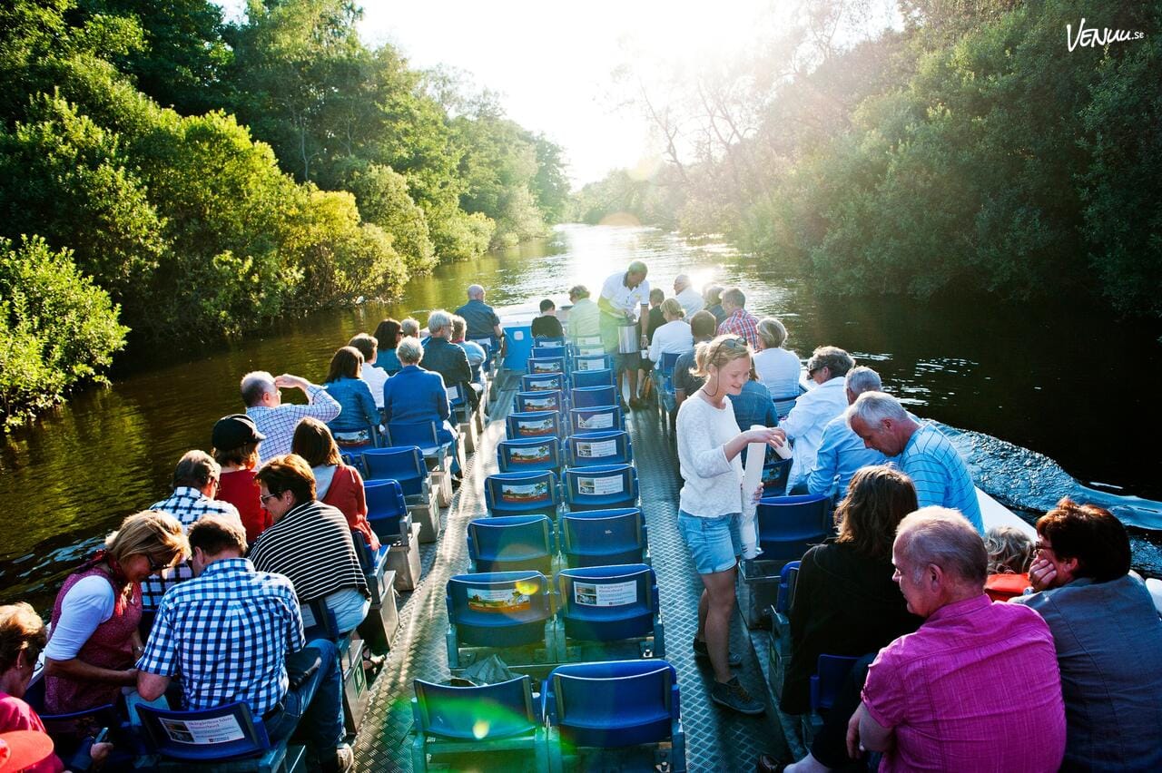 En naturskön vy av en Paddan-båt som glider fram på Göteborgs kanaler med glada passagerare.