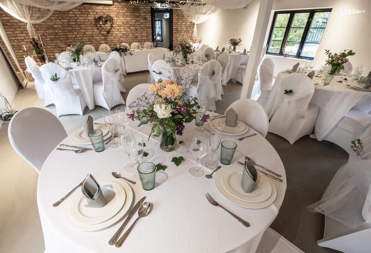 En modern och ljus festlokal med stora fönster som visar en naturskön omgivning.