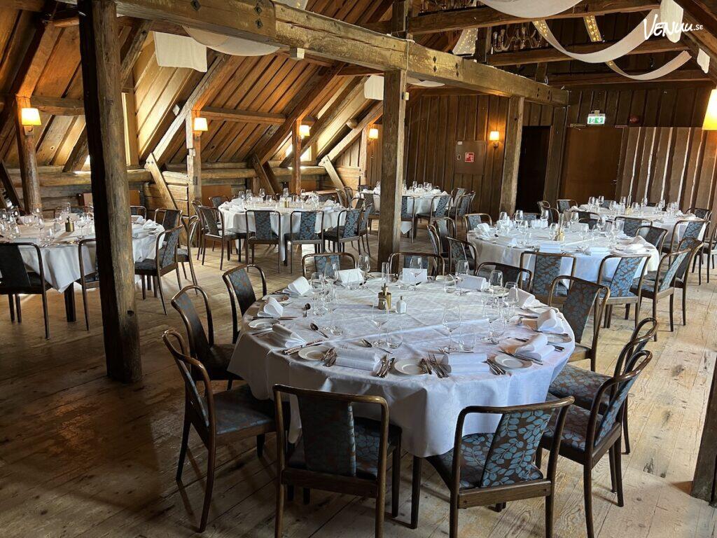 En elegant restauranglokal med maritim inredning och utsikt över vattnet, dukat för en festlig middag.