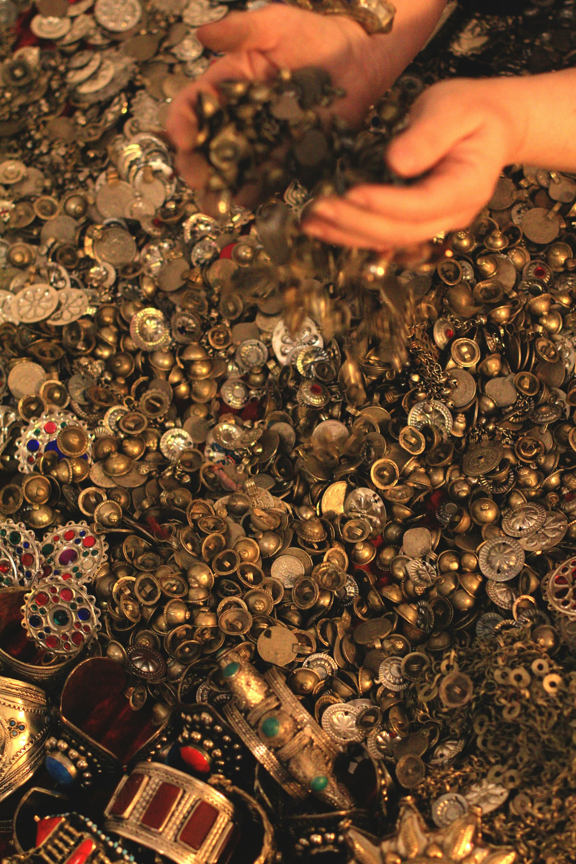 Barnhänder gräver i en hög med guldmynt och glittriga smycken – perfekt skatt för ett barnkalas.