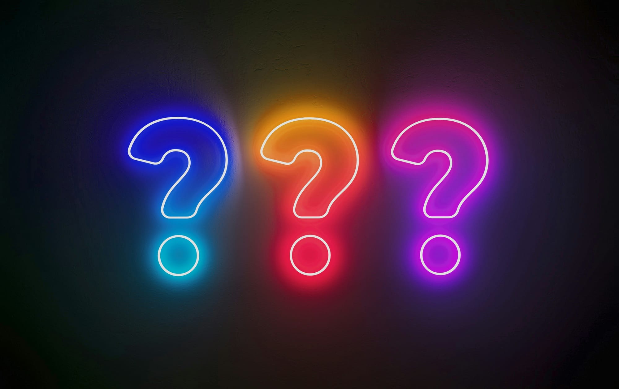 Tre neonfärgade frågetecken i blått, orange och rosa mot en mörk bakgrund – perfekt för ett festligt quiztema.