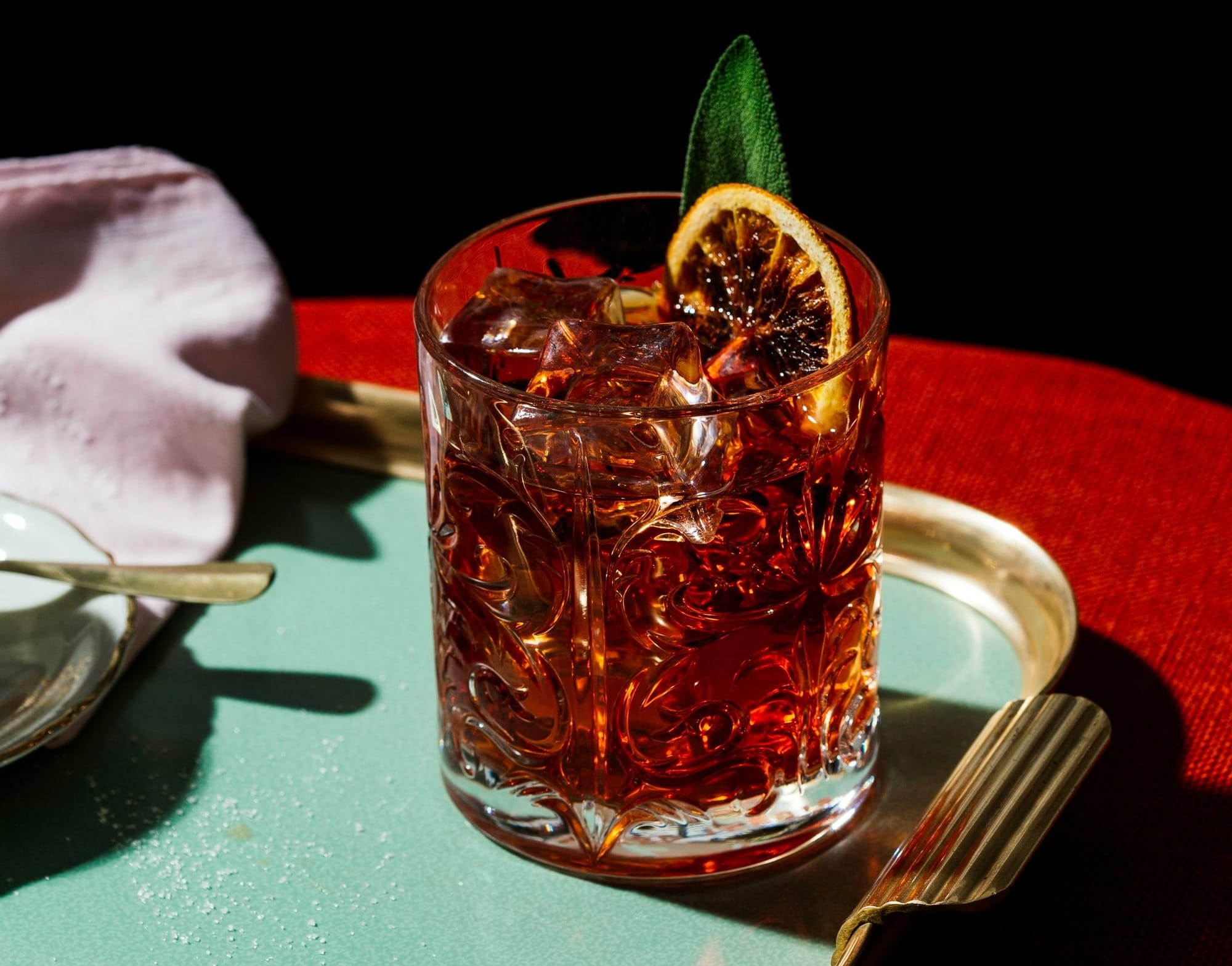 Klassisk Negroni drink serverad i old fashioned-glas med stora isbitar och apelsinzest
