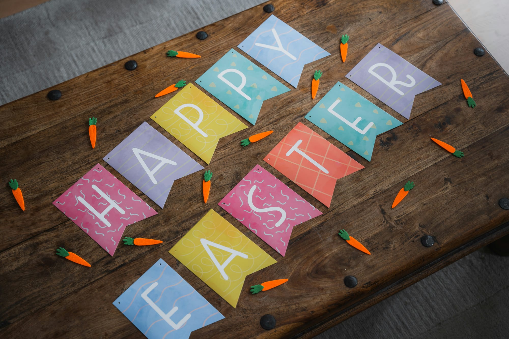Färgglad "Happy Easter"-girlang och morotsdekorationer på träbord – perfekt detalj för en kreativ och lekfull påskfest.