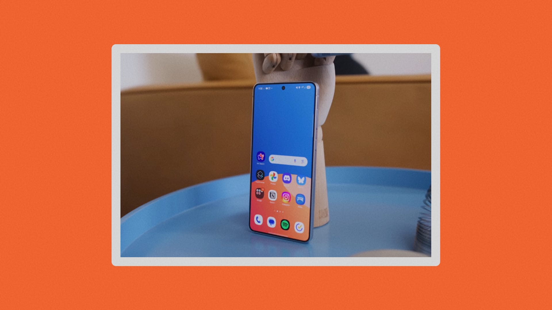 S25 Edge leaning against a wooden hand on a blue table