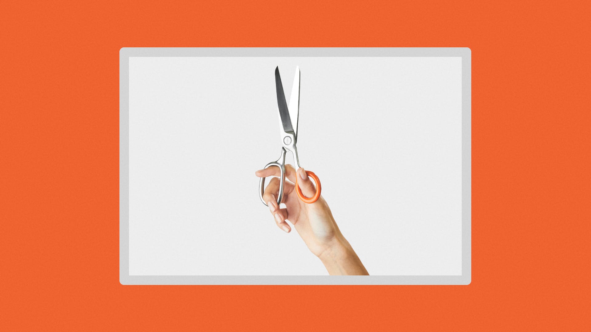 Image of a hand holding up a pair of scissors.