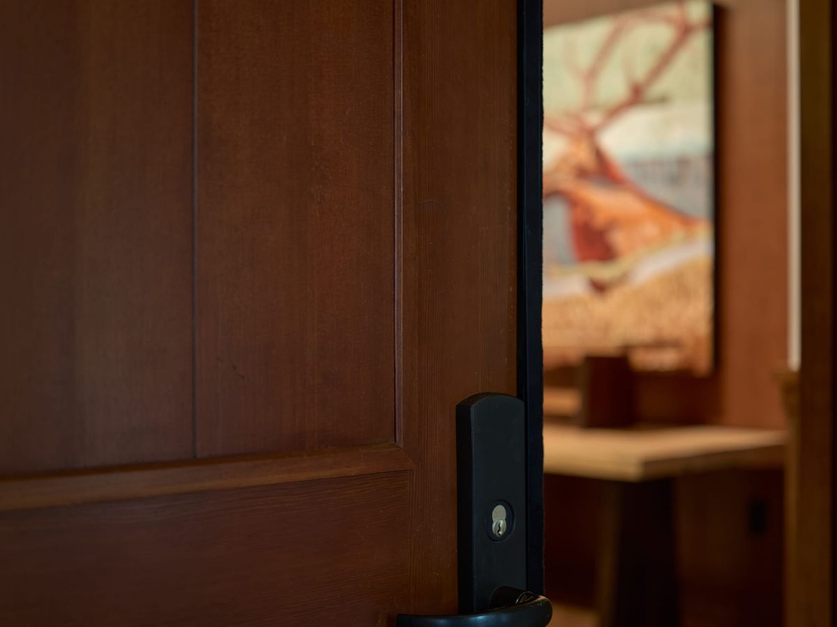 A paneled wood door standing ajar, opening onto a warm, softly lit room.