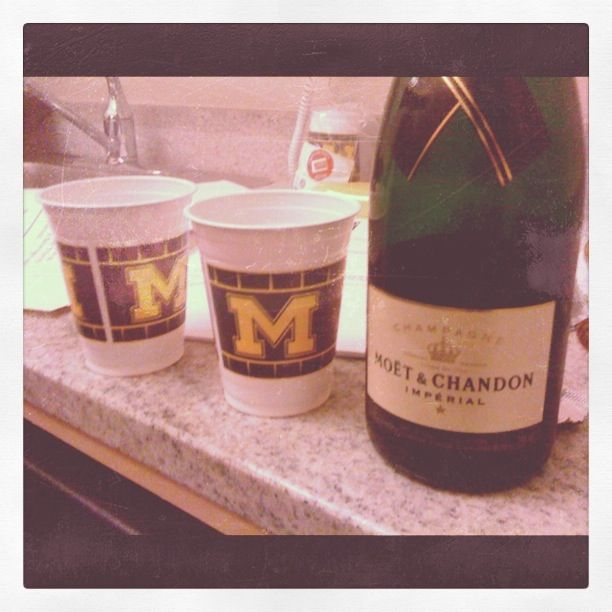 Bottle of Moët & Chandon Champagne on a counter next to two cups with the Michigan 'M' logo.