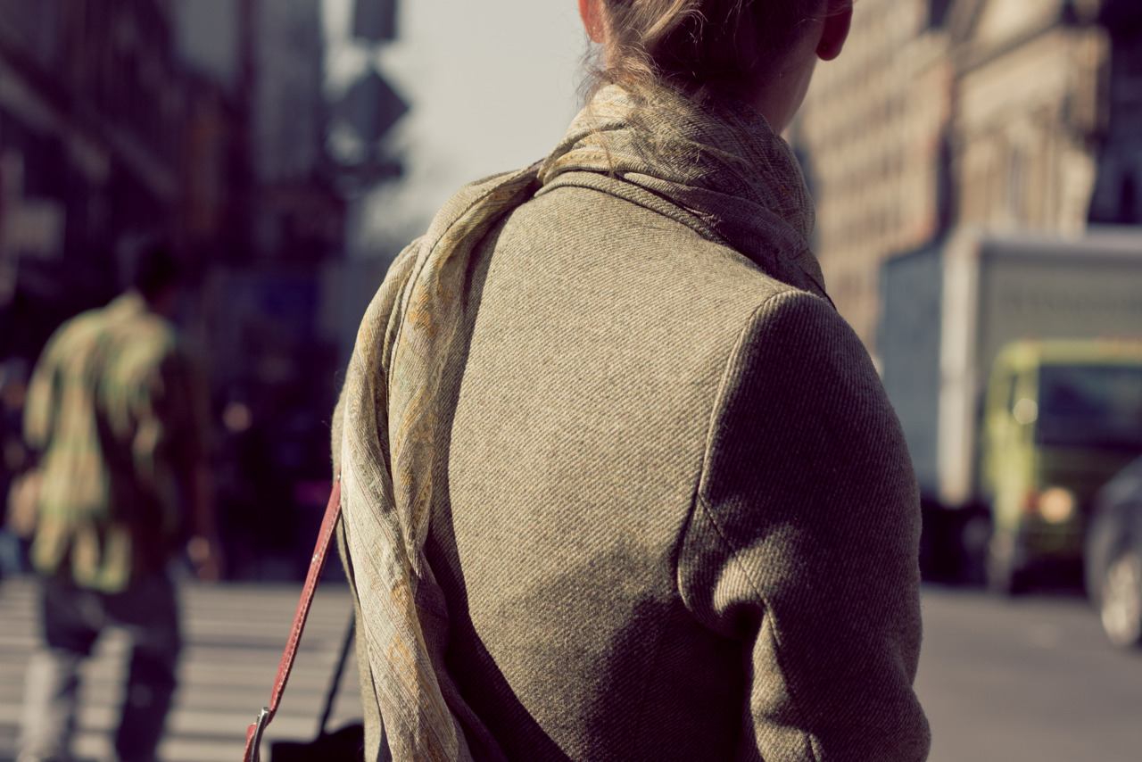 Caitlin in a tweed blazer and patterned scarf waiting at a crosswalk in New York City.
