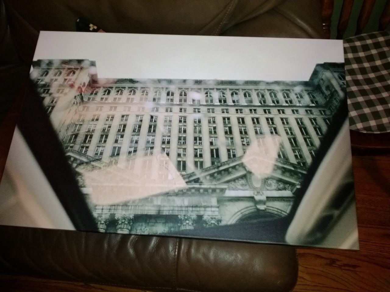 Canvas print on a leather sofa showing Michigan Central Station in Detroit through an open car sunroof.