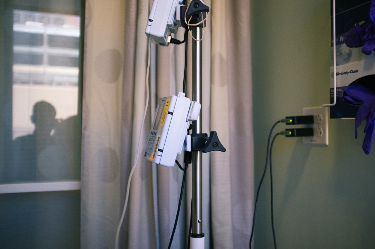 Hospital room IV pump and medical monitor mounted on a metal pole beside curtains.