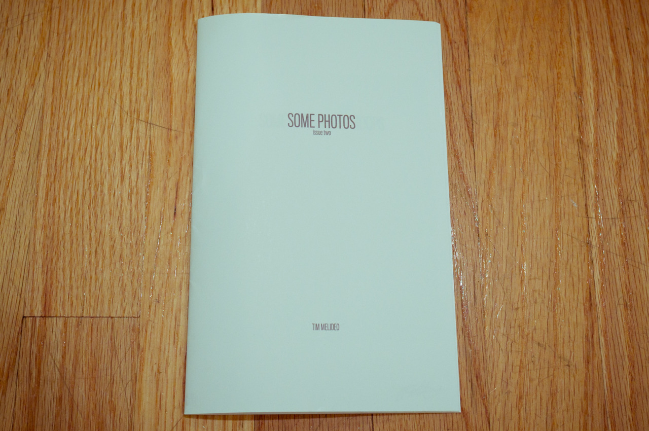 Pale mint green cover of Tim Melideo's photo zine titled 'SOME PHOTOS Issue two' resting on a light hardwood floor, captured with a Fujifilm FinePix X100.