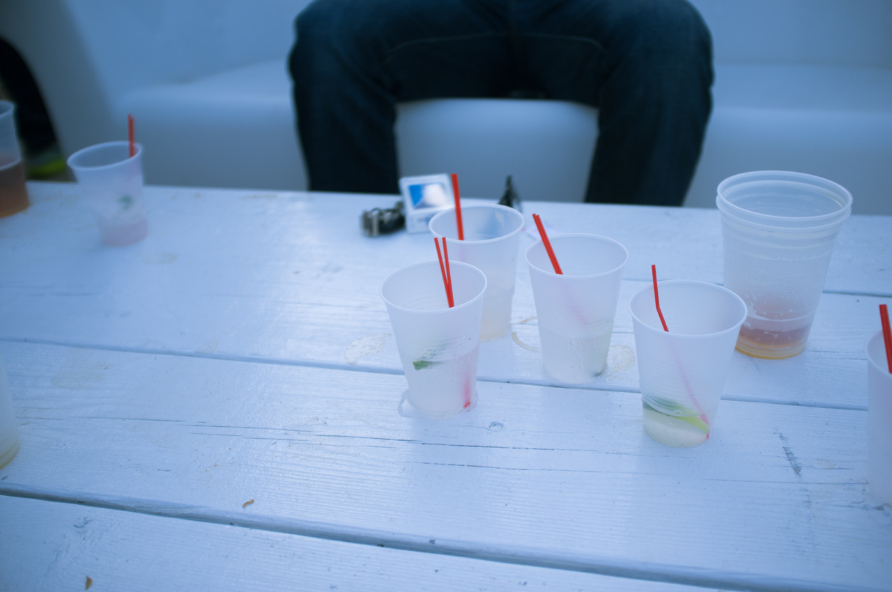 Cocktail cups with red straws and lime wedges on a white slatted outdoor table at Beekman Beer Garden.
