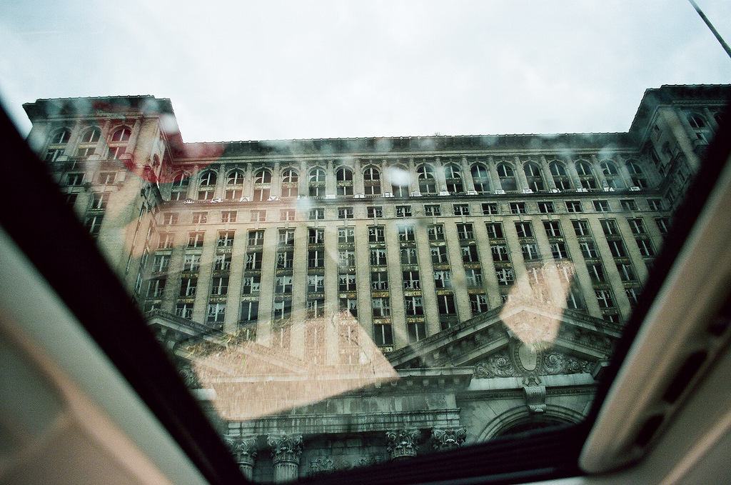 Looking up through a car sunroof at the grand facade of abandoned Michigan Central Station in Detroit.