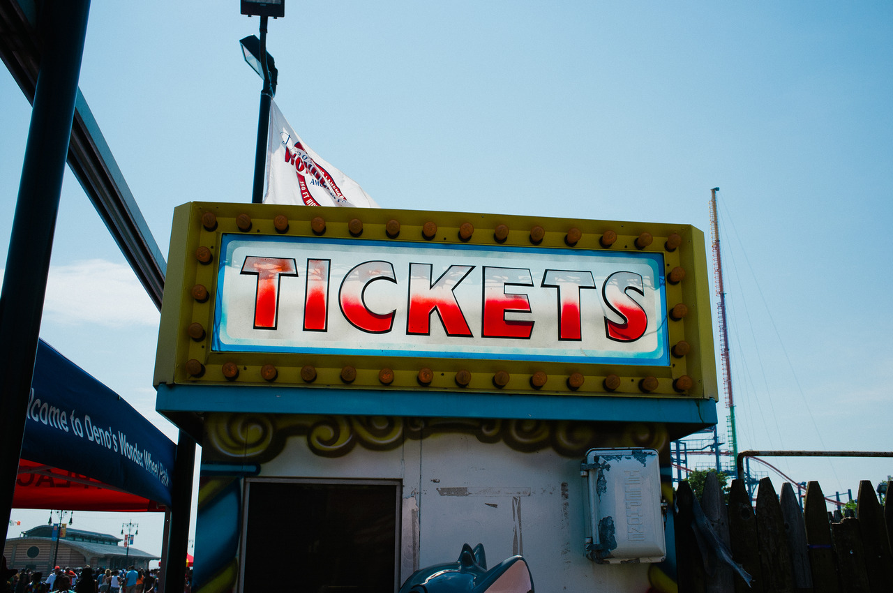 Vintage carnival ticket booth at Deno's Wonder Wheel Park with an illuminated red 'TICKETS' marquee sign.