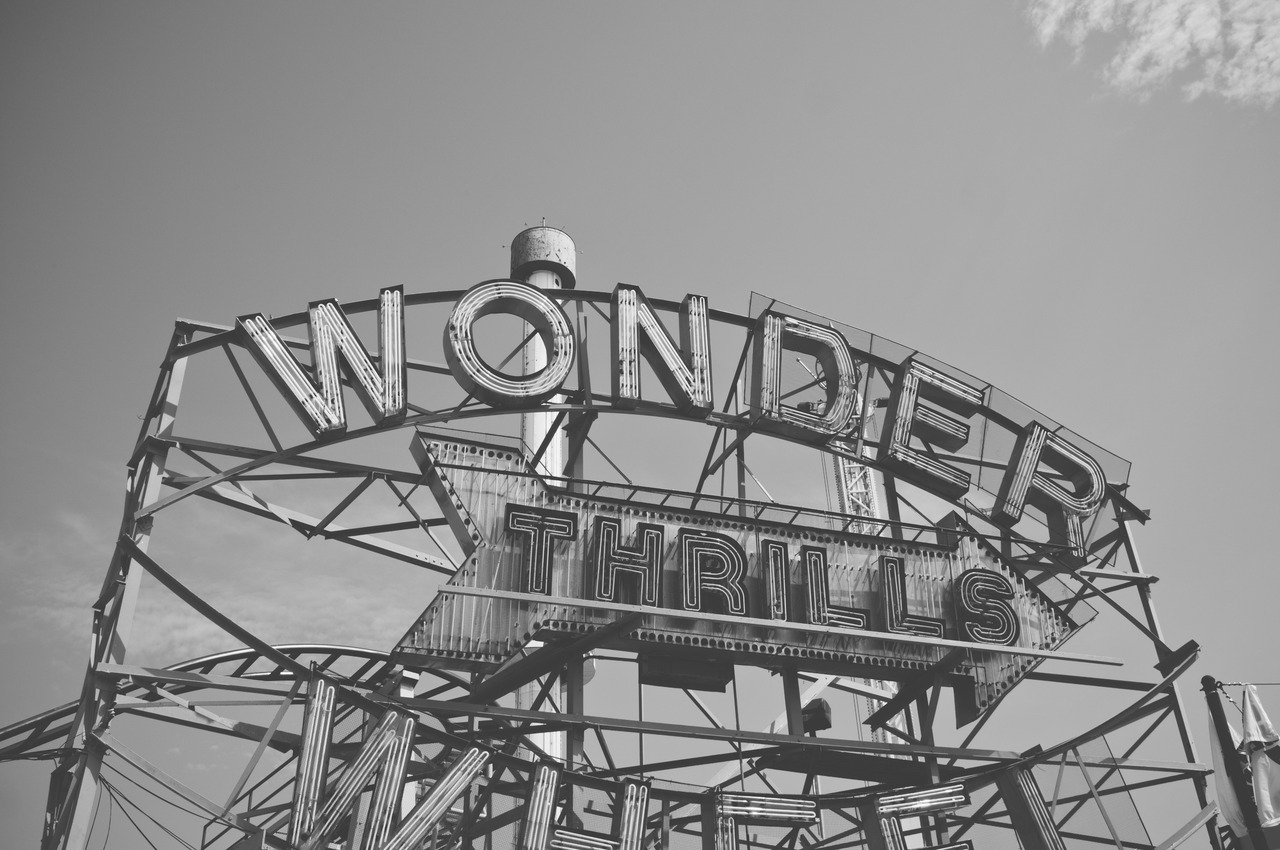 Neon marquee sign reading 'WONDER WHEEL' and 'THRILLS' atop the amusement park structure at Coney Island.