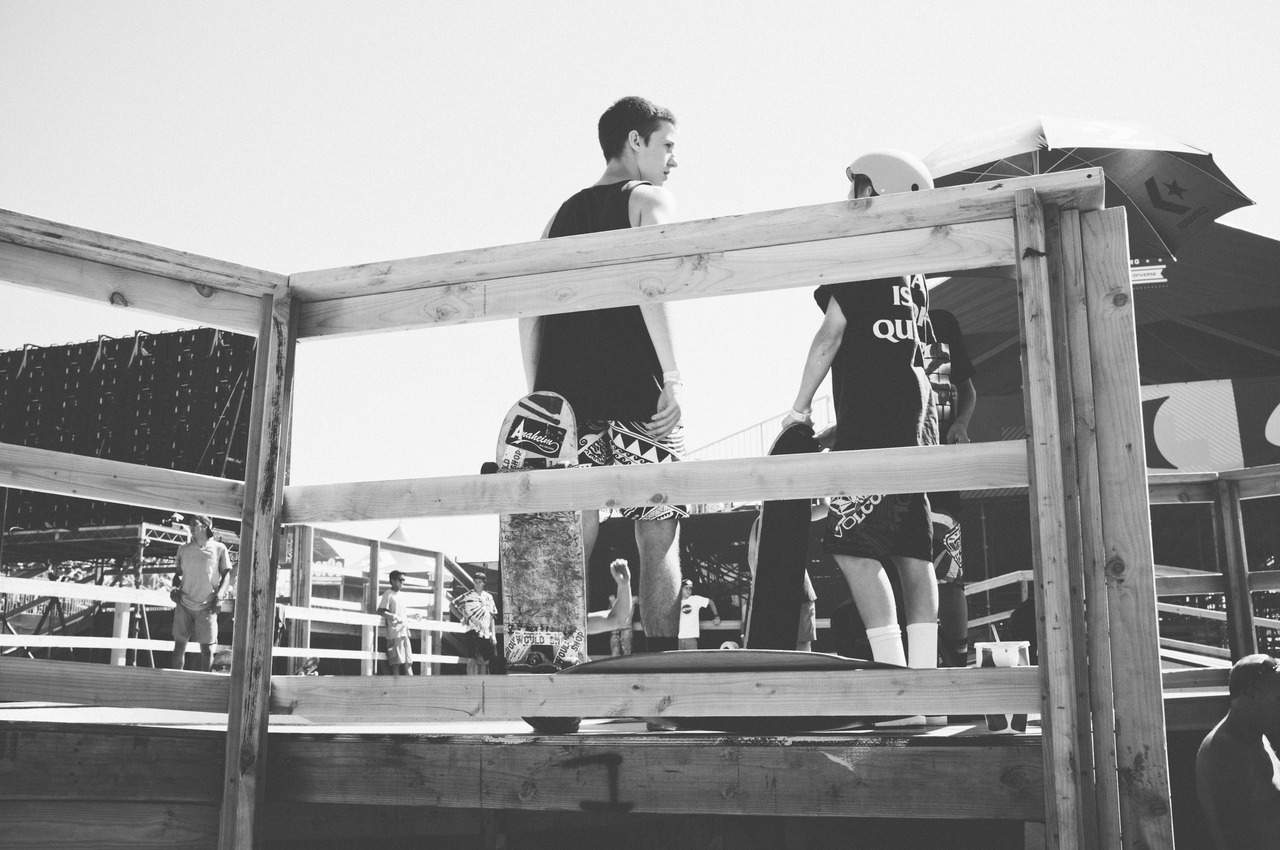 Two teenage skaters holding skateboards atop a ramp deck under an umbrella at the US Open of Surfing.