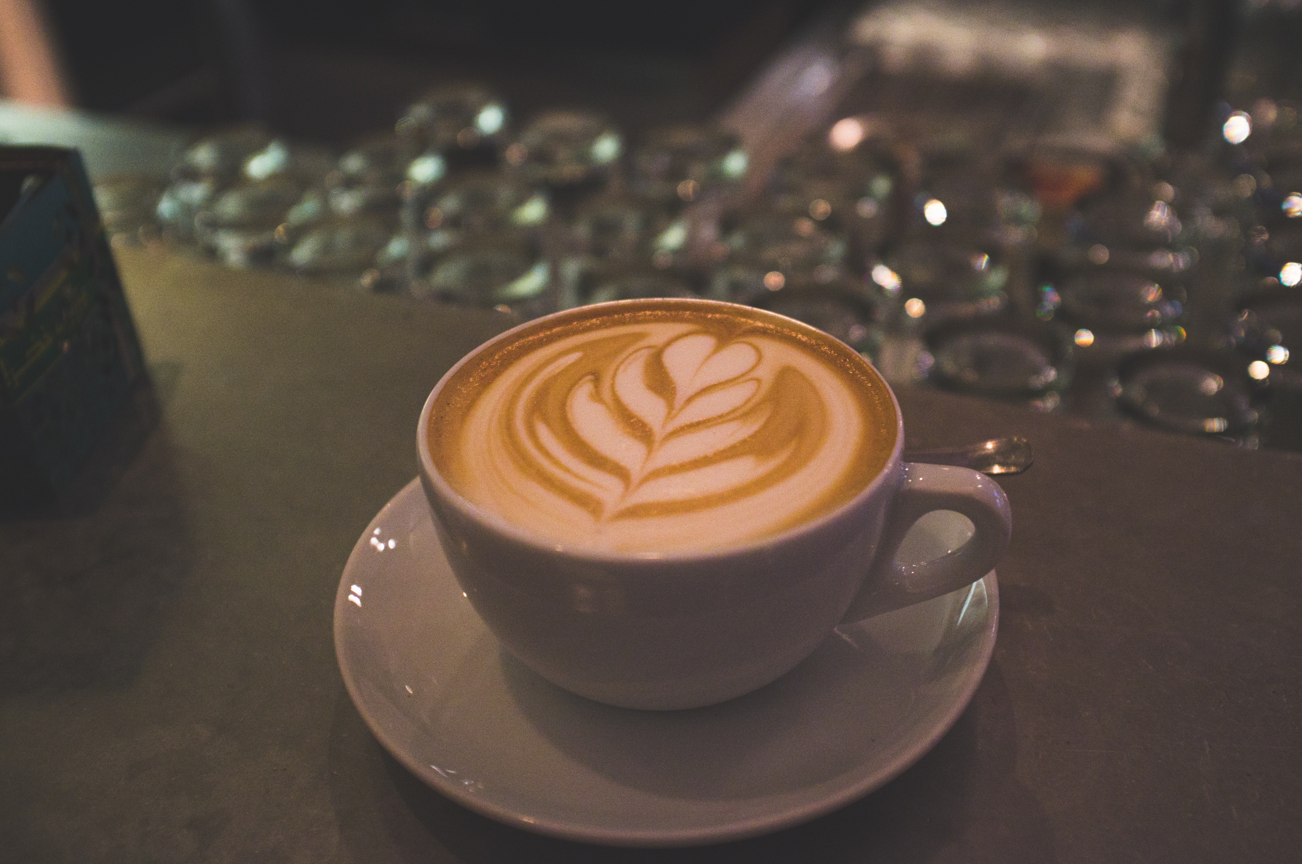 Cup of coffee with delicate rosetta leaf latte art in white ceramic cup on cafe wooden countertop in Switzerland.