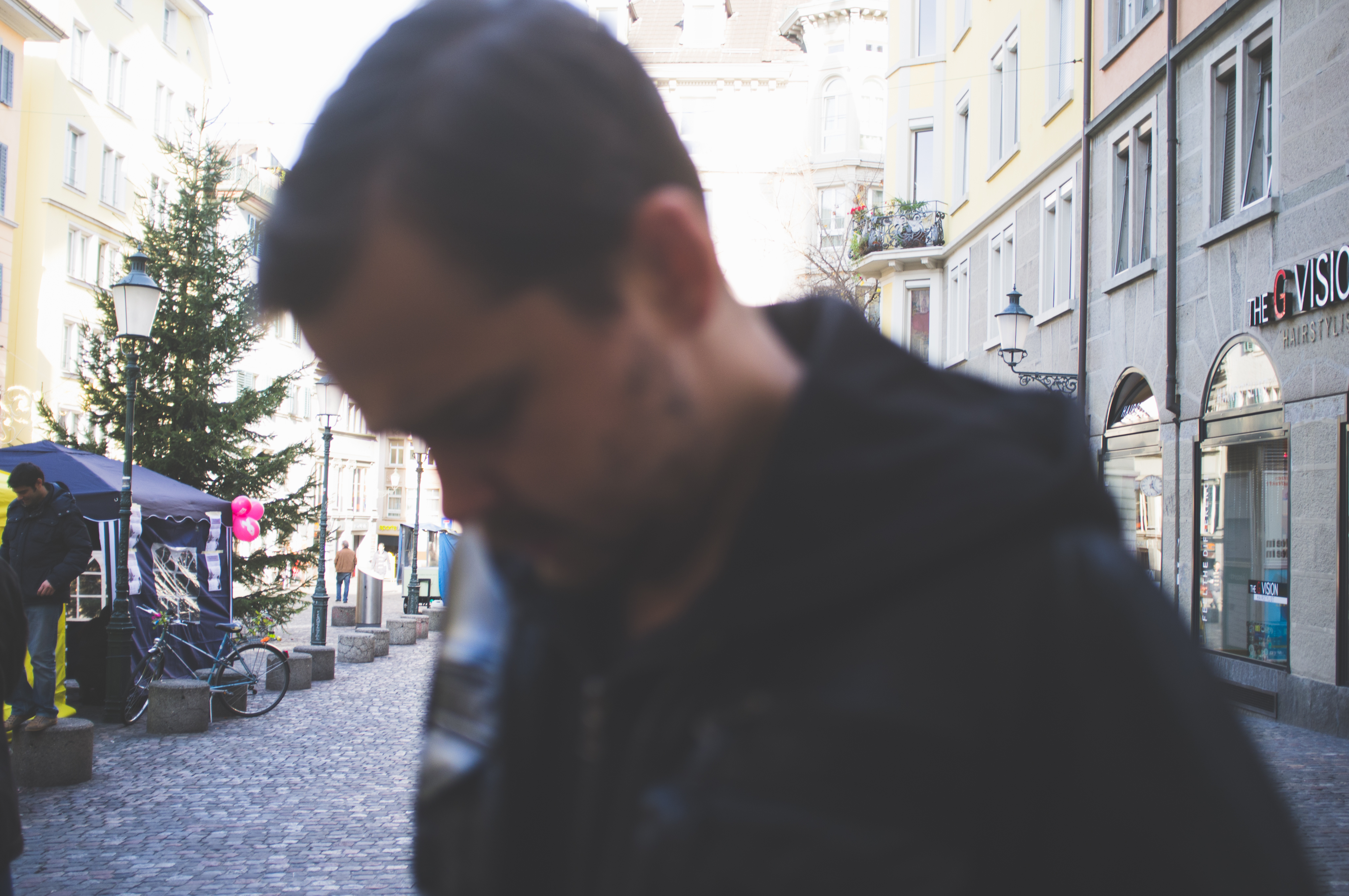 Pedestrians walking down a Zurich cobblestone street lined with festive holiday market stalls.