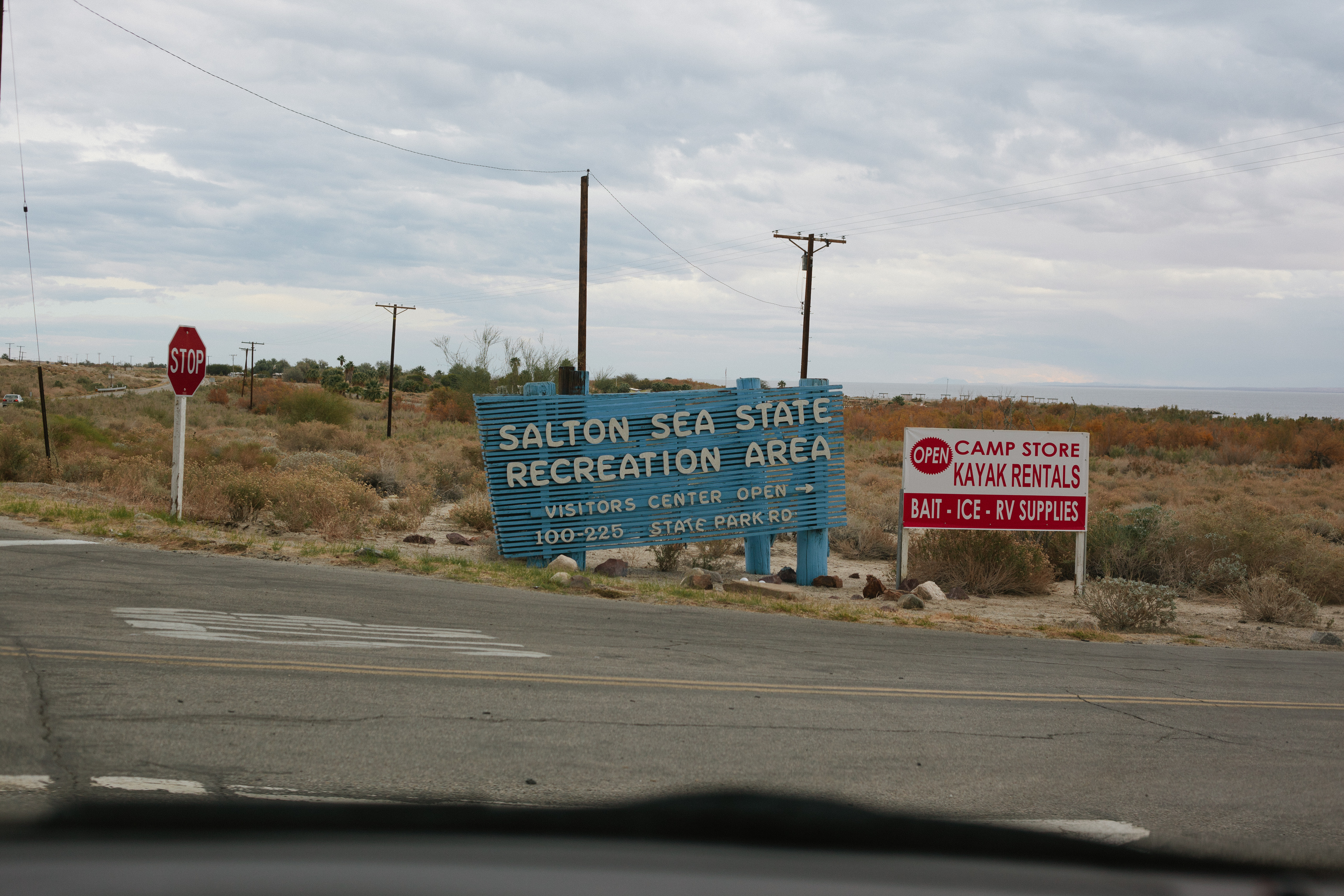 Rustic blue wooden slatted entrance sign for 'SALTON SEA STATE RECREATION AREA' along the desert roadside.