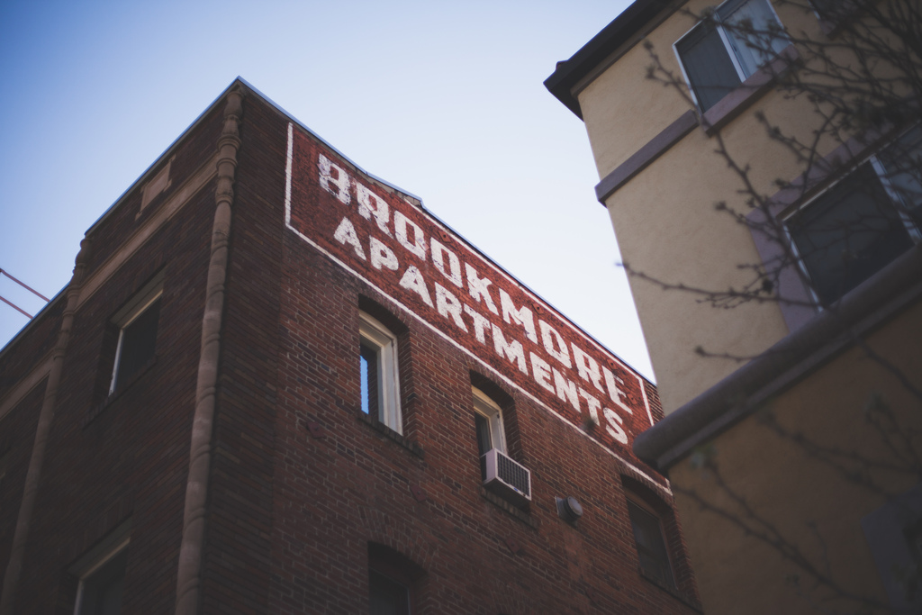 Faded ghost sign lettering on the red brick exterior of the Brookmore Apartments building.