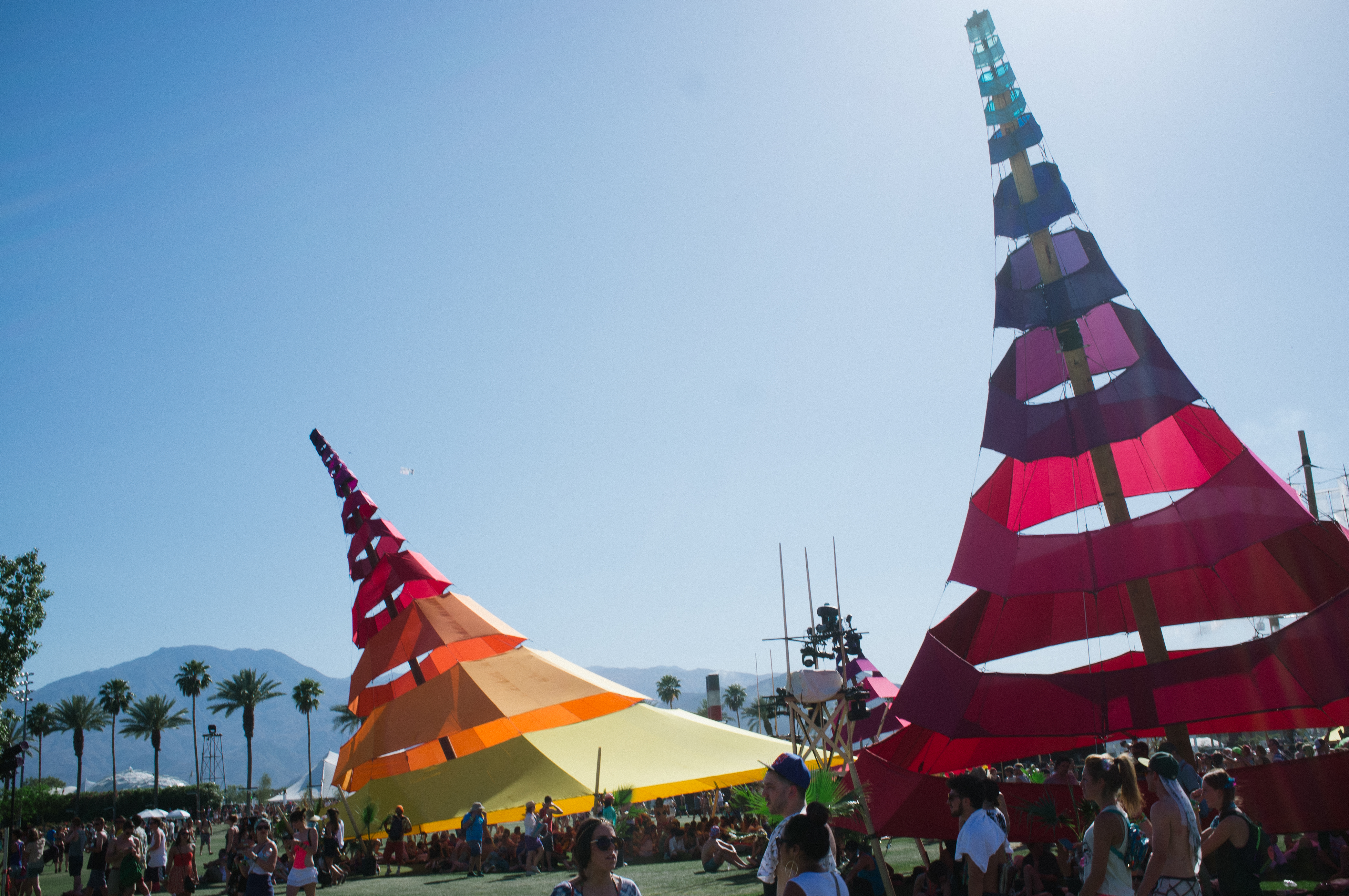 Colorful geometric fabric shade pavilions spiraling into a blue desert sky at Coachella.
