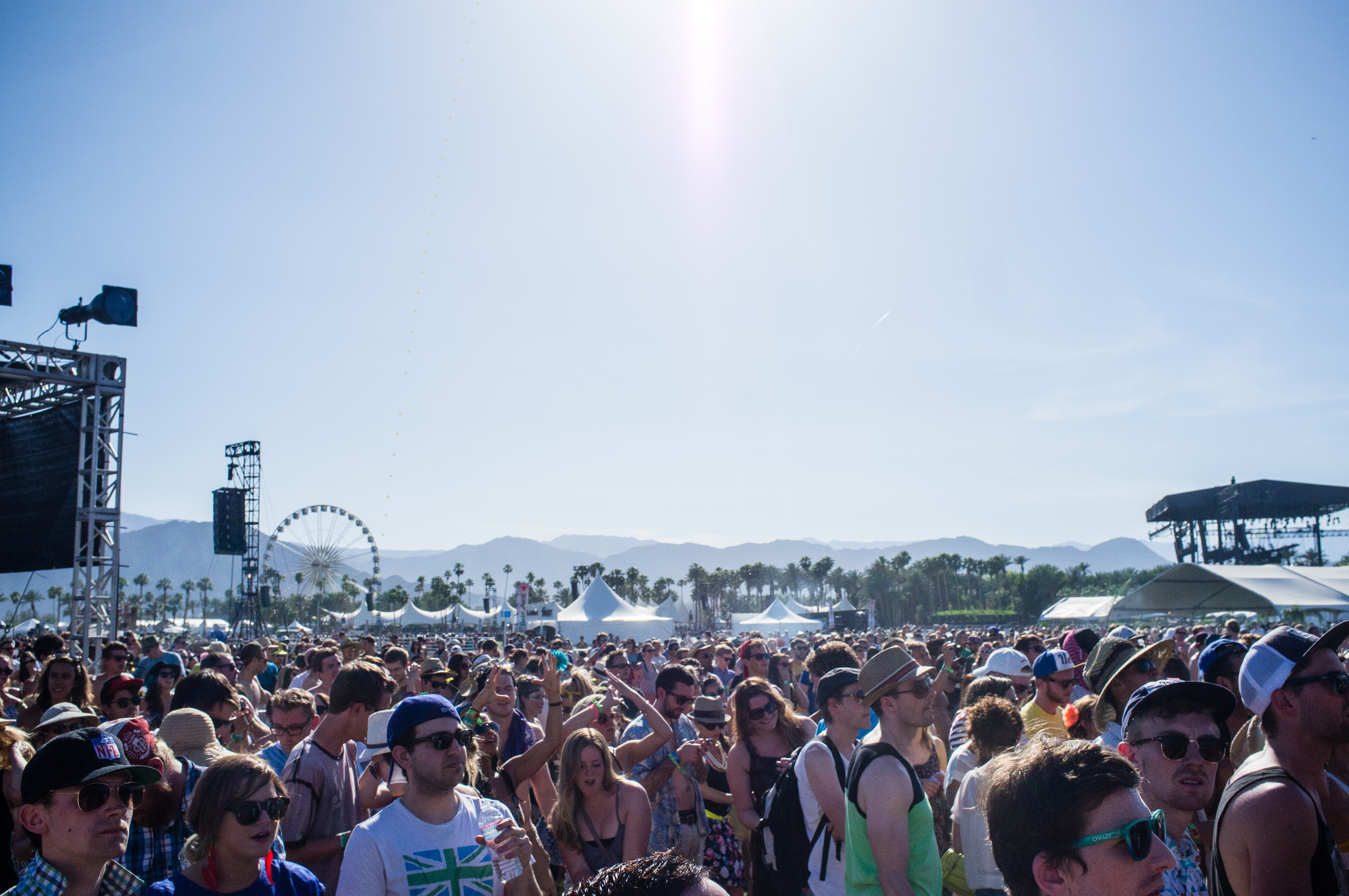 Dense crowd of festival attendees under desert sunshine with mountains at Coachella.