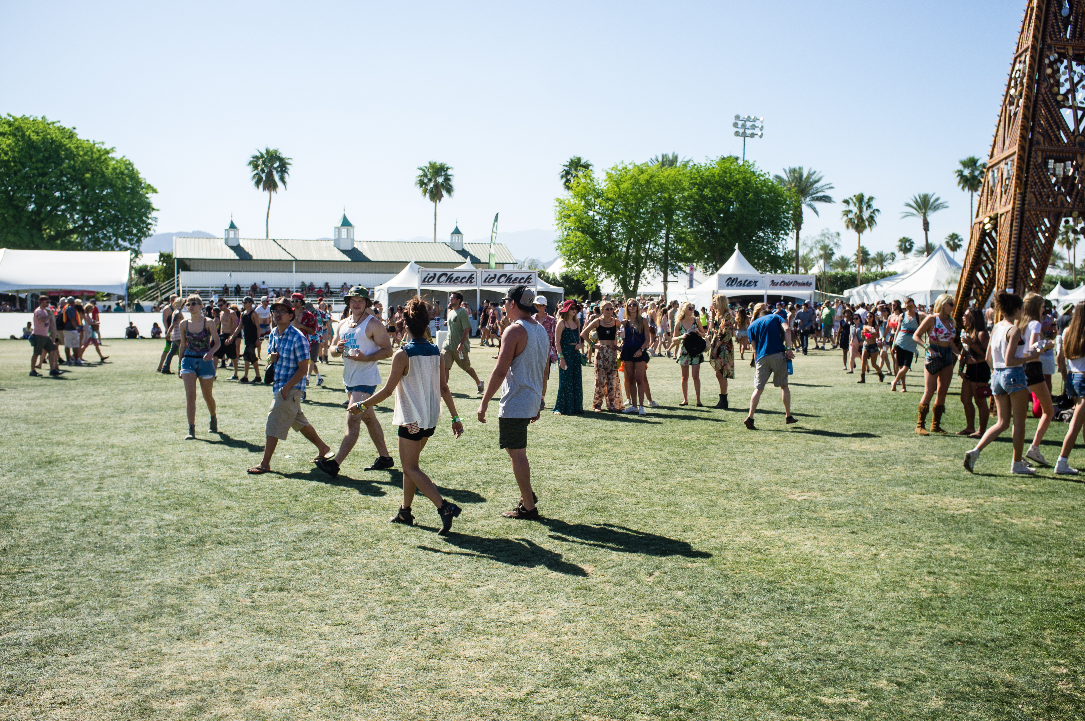 Festivalgoers walking past ID Check and Water tents toward a wooden tower at Coachella.