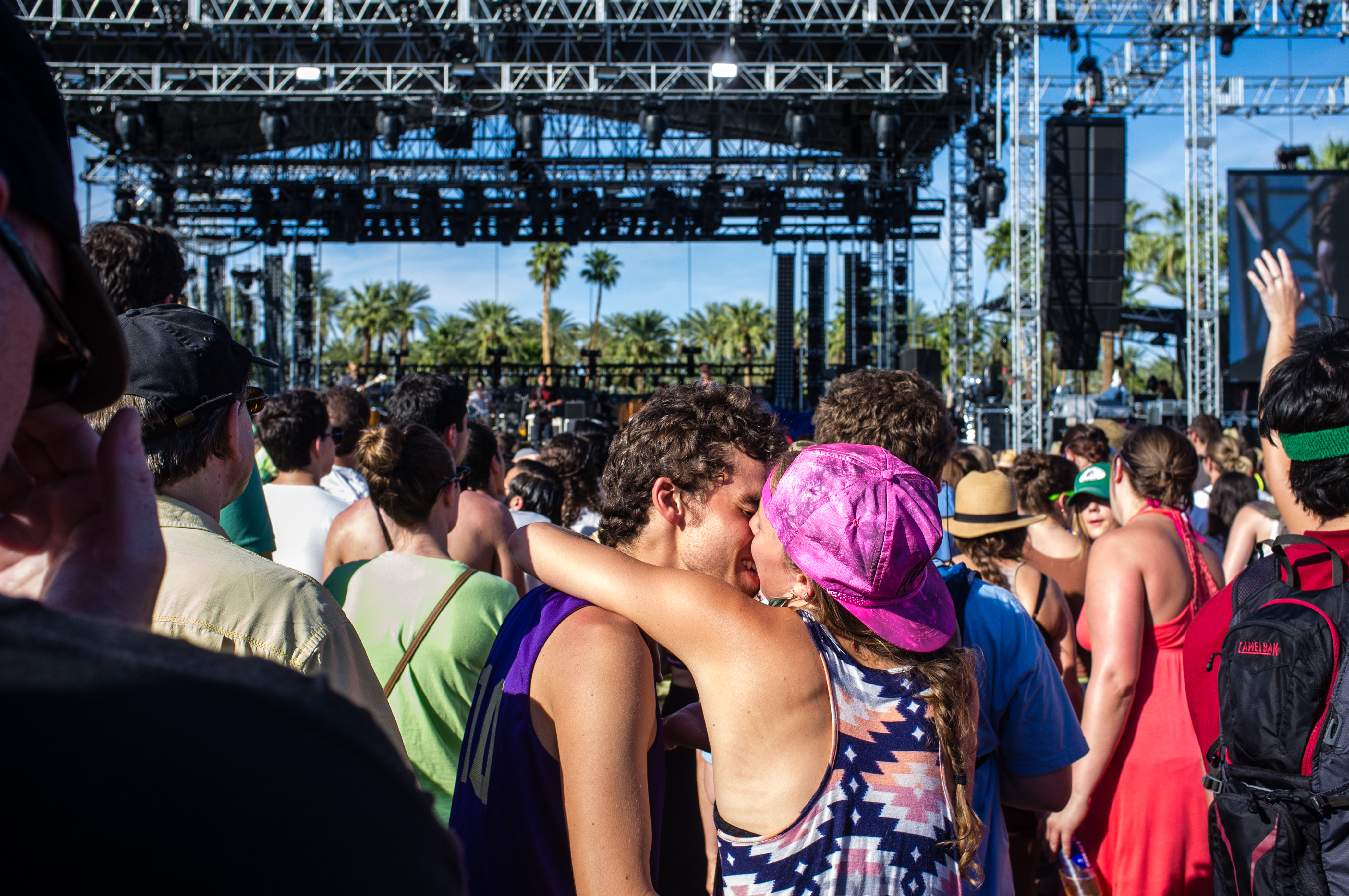 Young couple embracing and kissing in a festival crowd before an outdoor stage at Coachella.