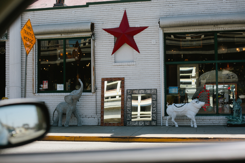 Eclectic storefront featuring a red metal star, elephant statue, mirrors, and a pig sculpture.