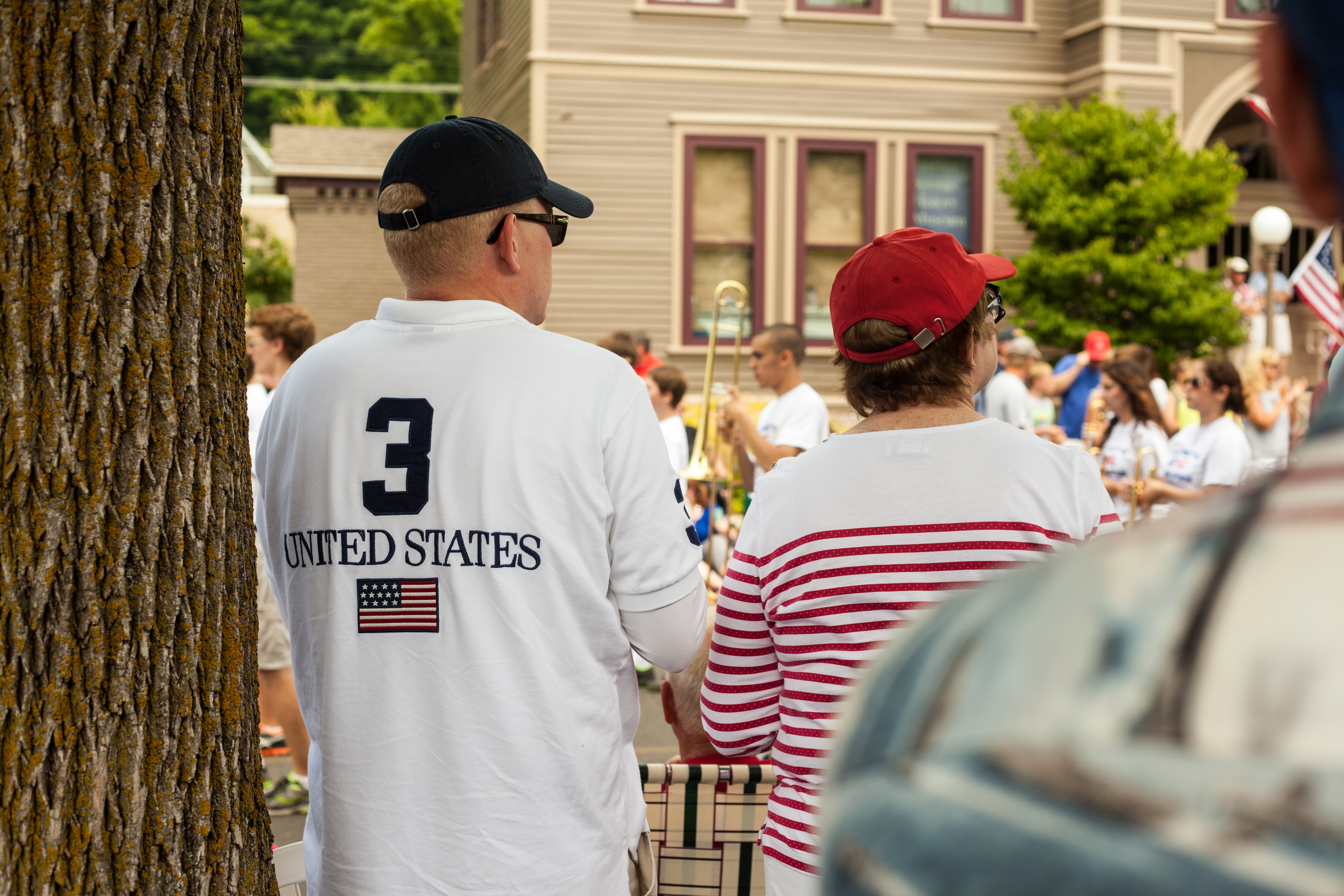 Spectators in patriotic attire watching a marching brass band at a parade in Harbor Springs.