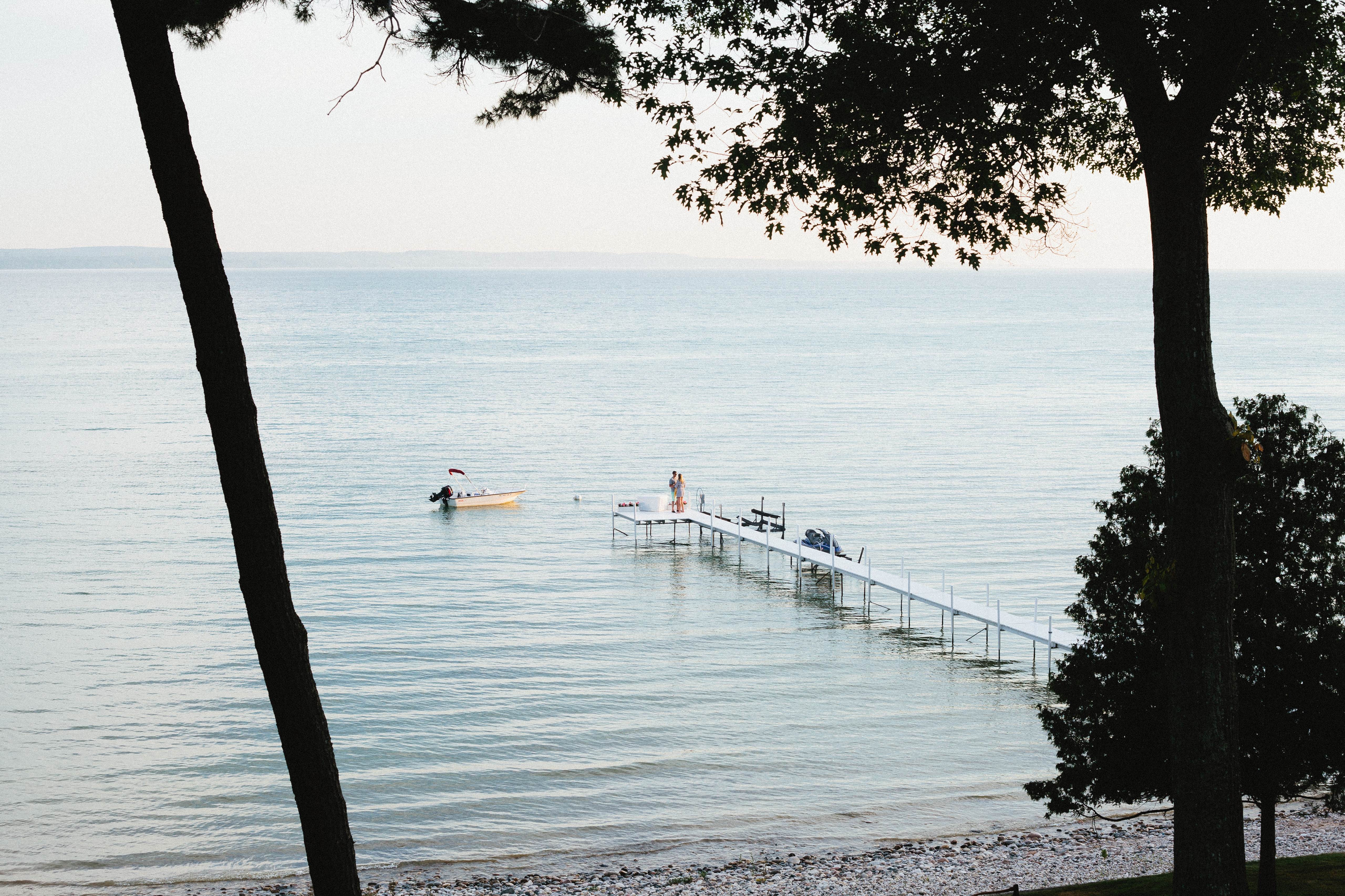 White wooden dock extending into calm blue water with a moored motorboat in Harbor Springs.