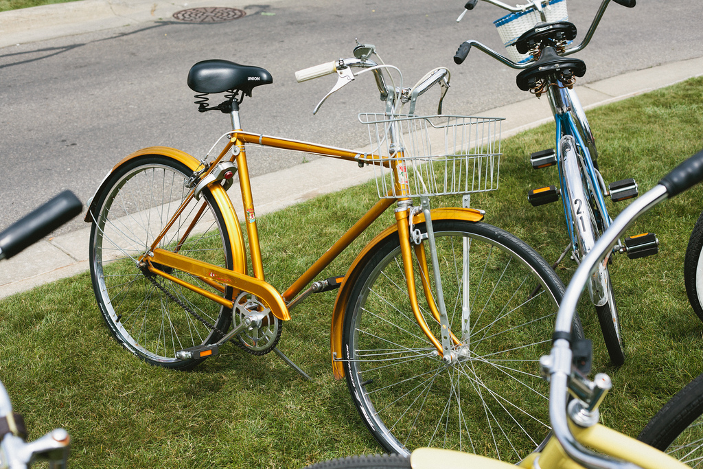 Vintage gold cruiser bicycle with a white wire basket parked on green lawn in Harbor Springs, Michigan.