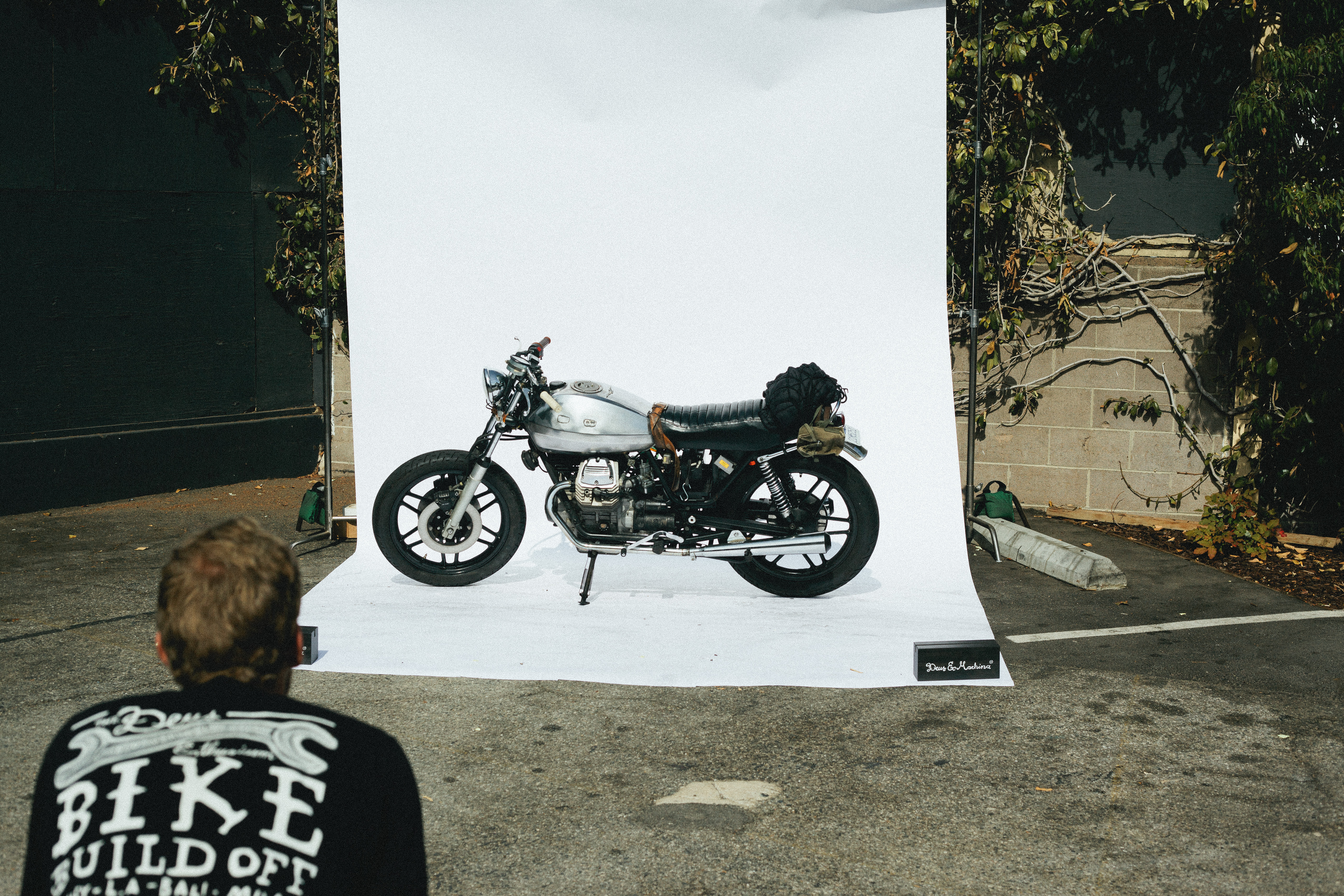 Custom cafe racer motorcycle with a silver tank on an outdoor white backdrop at Deus Bike Build Off.