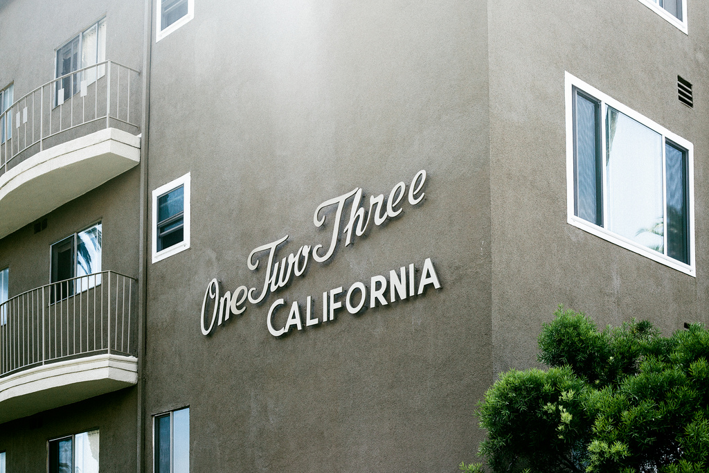 Mid-century apartment building facade with architectural lettering reading 'One Two Three CALIFORNIA'.