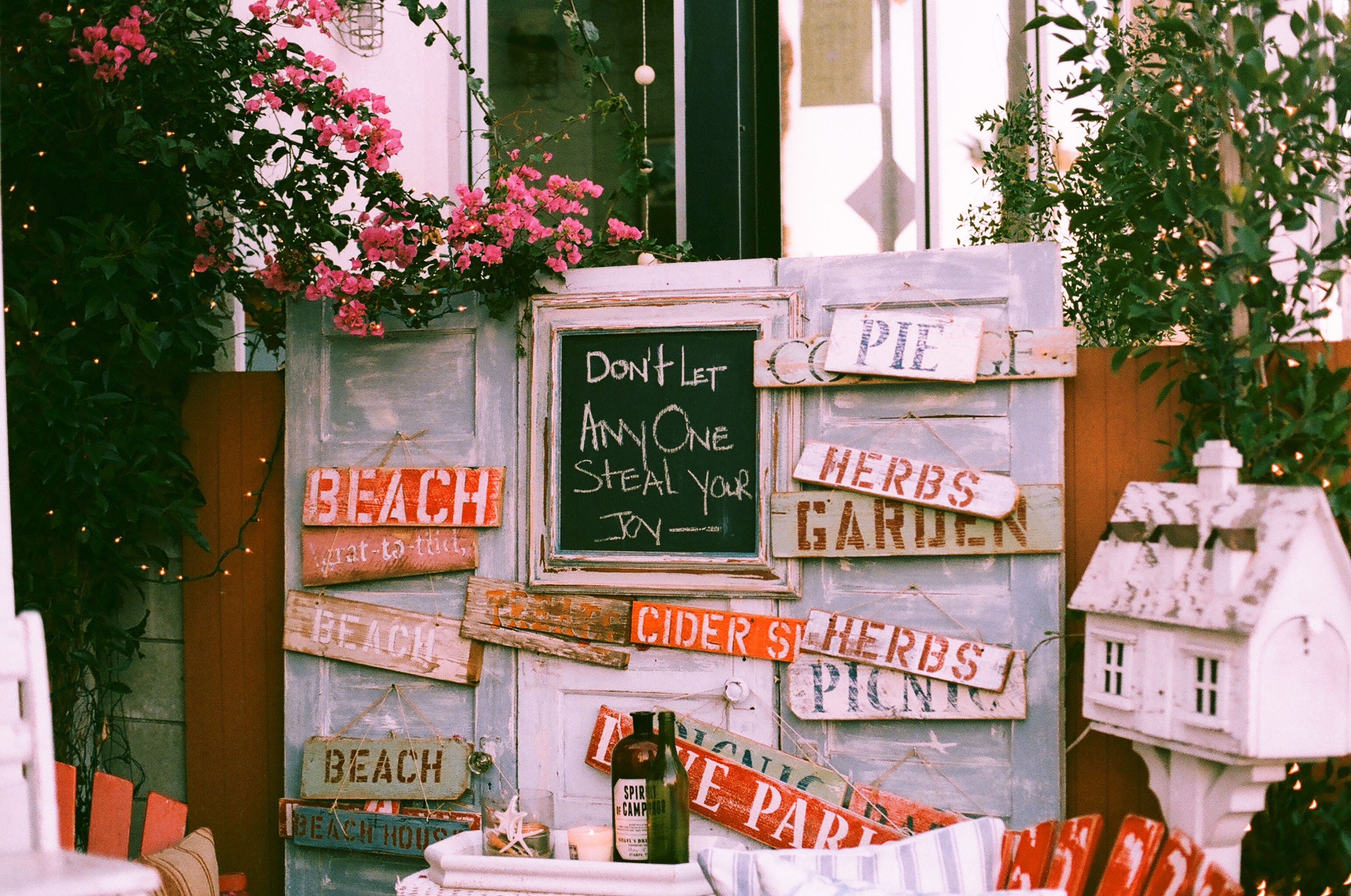 Rustic display with signs reading 'BEACH', 'HERBS', 'GARDEN', and 'Don't let anyone steal your joy'.