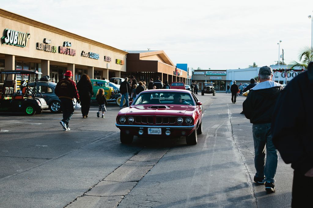 Cherry red vintage Plymouth Barracuda driving past spectators at the Donut Derelicts car show.