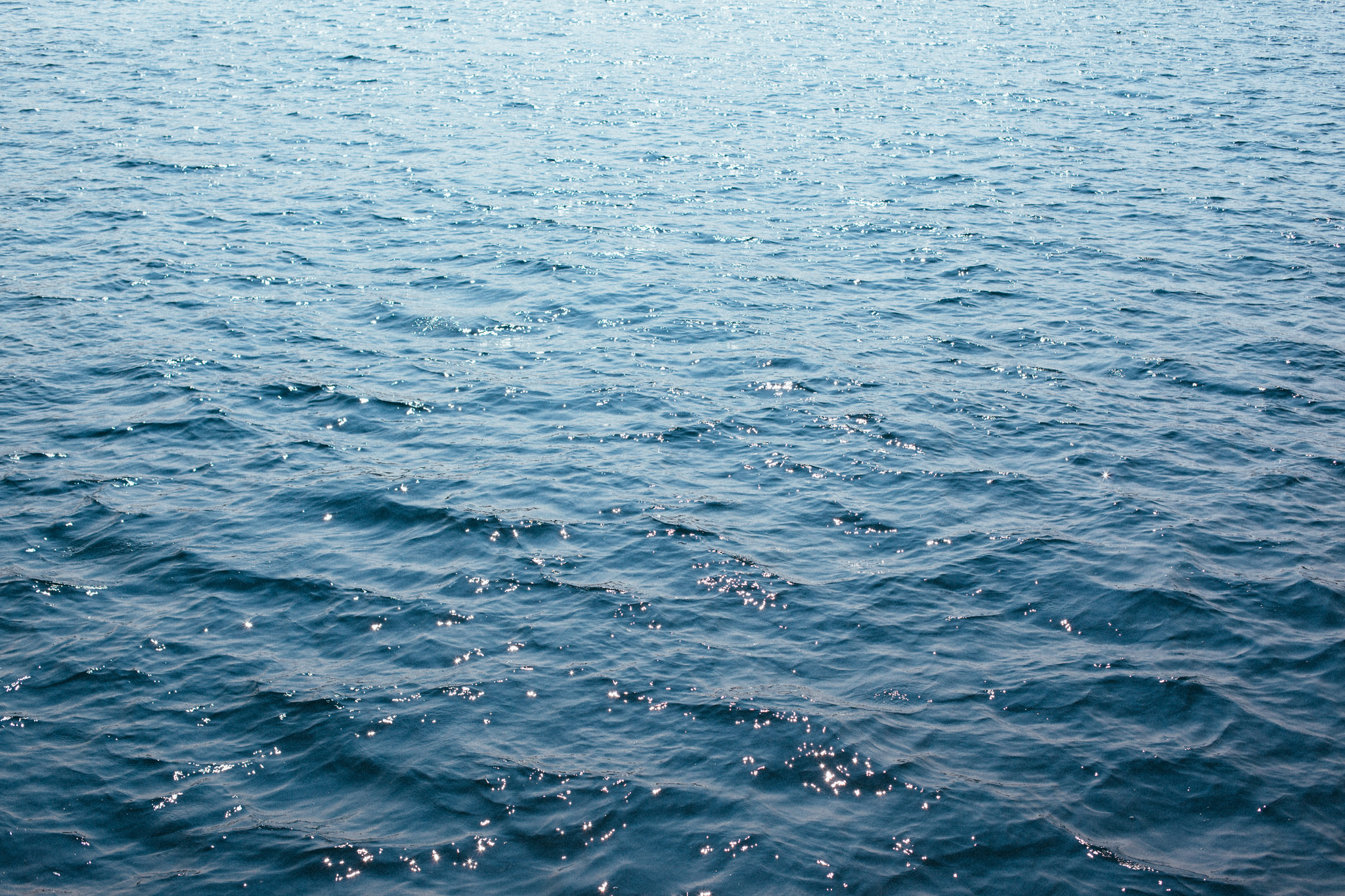 Sunlight sparkling across the rippling deep blue surface of Lake Michigan water, shot with a Canon 5D Mark II.