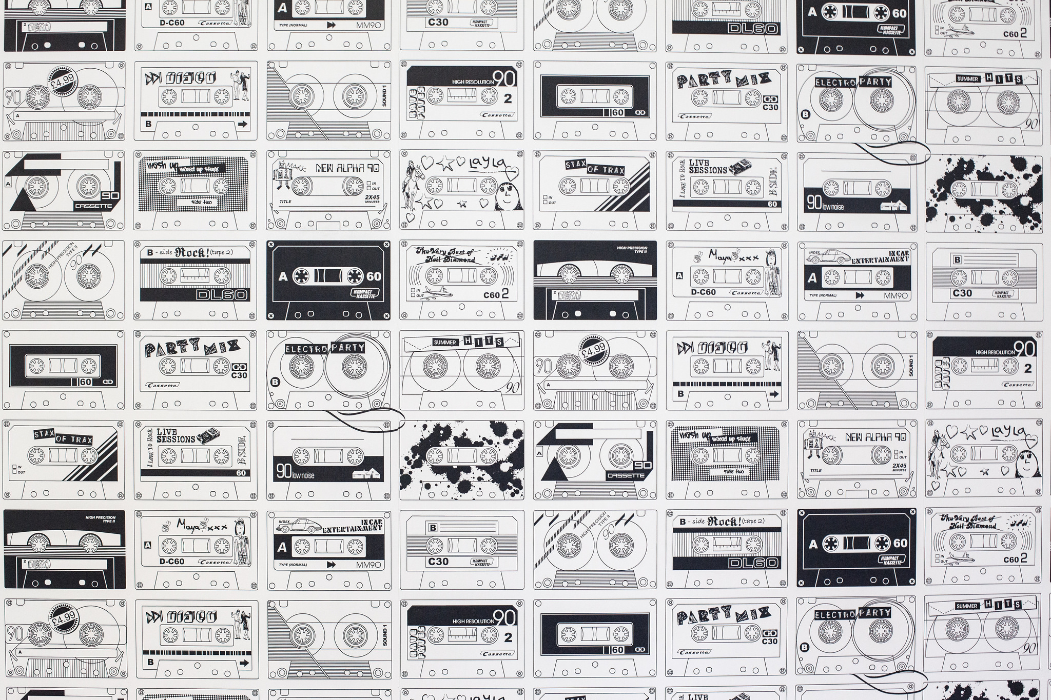 Wall covered in graphic wallpaper pattern of vintage cassette tapes with hand-drawn labels and sleeves.